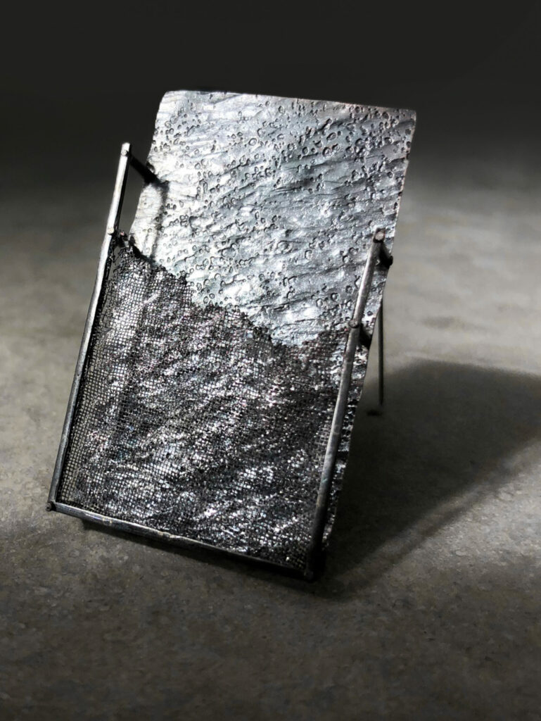 grey rectangle brooch on light grey concrete background